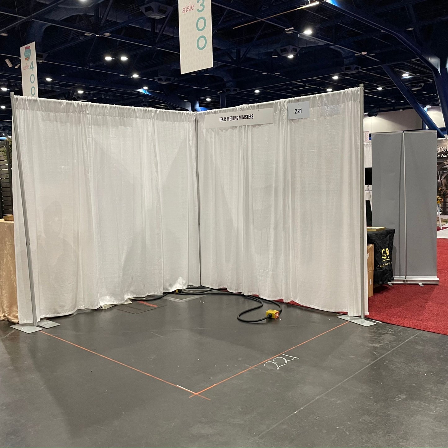 8'x8' corner trade show booth standing on concrete with white drape.